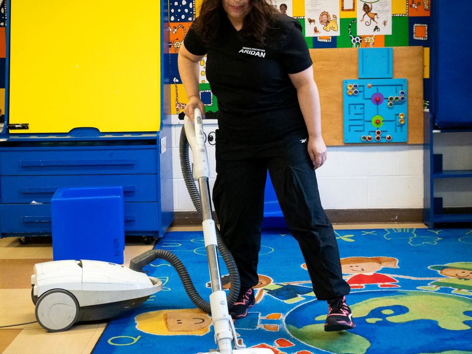 Employée ARIDAN qui passe l'aspirateur sur le tapis d'une garderie
